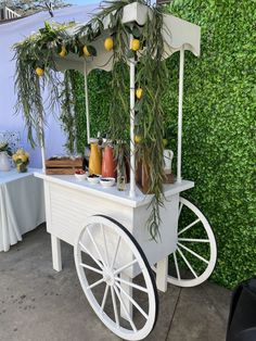 a white cart with lemons on it sitting in front of a green wall and table