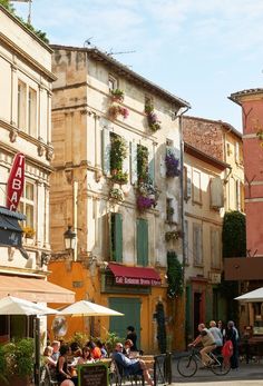 people are sitting at tables in the middle of an alleyway with shops and restaurants