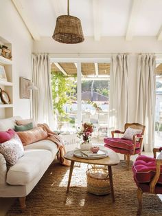 a living room filled with furniture and a large window covered in curtains on top of it