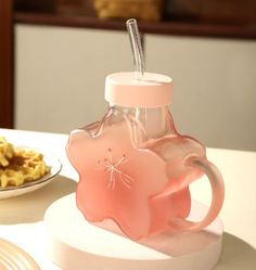 a pink glass cup sitting on top of a table next to some waffles