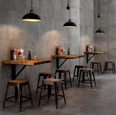 a restaurant with wooden tables and stools in front of a wall that has lights hanging from it