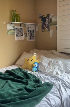 there is a stuffed animal on the bed in this small room with white sheets and green blankets