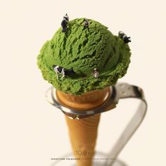 a scoop of green ice cream on top of a wooden cone with cows in it