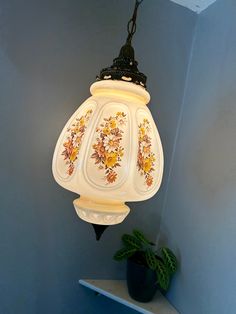 a lamp hanging from the ceiling in a room with blue walls and a potted plant