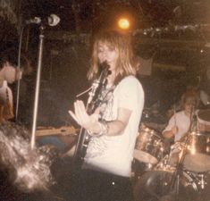 a man standing in front of a microphone on top of a stage with other people