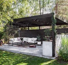 an outdoor living area with couches and tables in the middle of it, surrounded by greenery