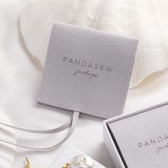 a pair of earrings sitting on top of a white table next to a box with the word pandasew