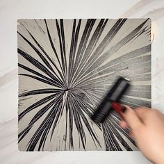 a person using a brush to paint a painting on a wall with black and white stripes