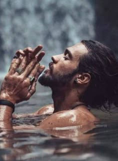 a man in the water holding his hands up to his chest and looking at something