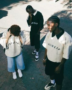 three young men standing on the street talking to each other