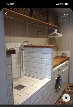 a washer and dryer in a small room with shelves on the wall behind them