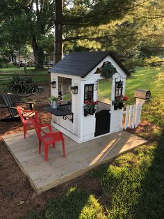 a small white house sitting on top of a wooden deck next to a red chair