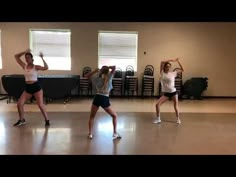 three young women are practicing their moves in a dance studio with chairs and windows behind them