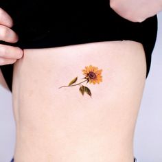 a sunflower tattoo on the side of a woman's stomach is seen in this image