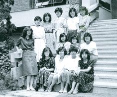 an old black and white photo of women sitting on the steps