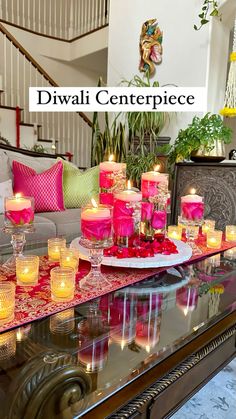 a table topped with lots of candles next to a couch covered in pink and red pillows