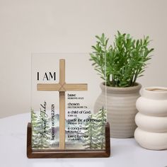 a wooden cross sitting on top of a table next to a vase and potted plant