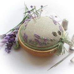 lavender flowers are sitting on the table next to sewing needles