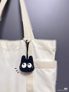 a white bag with a black cat on the front pocket and eyes drawn on it