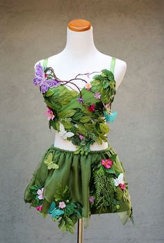 a dress made out of leaves and flowers on a mannequin