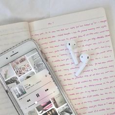 an iphone and ear buds laying on top of a book with pink writing in it