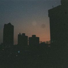 the city skyline is silhouetted at night with buildings in the foreground and an airplane flying overhead