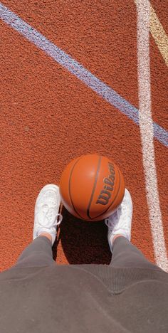 an overhead view of a person's feet with a basketball on the ground in front of them