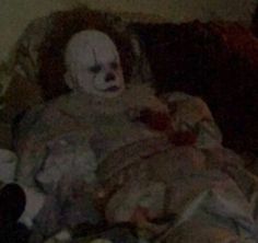 a creepy clown is sitting on the couch