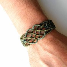 a man's arm with a bracelet on it that has an intricate knot in the middle