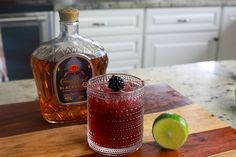 a bottle of booze next to a glass on a cutting board