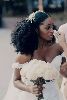 a woman in a white wedding dress holding a bridal bouquet and looking at the camera