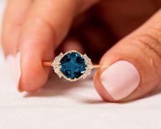 a woman's hand holding an engagement ring with a blue stone in the center