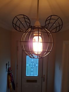 a mickey mouse head light fixture hanging from the ceiling in front of a door with a stained glass window