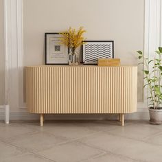 a wooden cabinet sitting next to a potted plant on top of a tiled floor