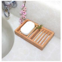 a soap dish sits on a wooden tray next to a white sink with pink flowers