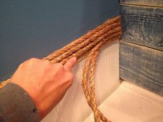 a man is holding a rope in front of some wood planks on the wall