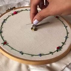 someone is using a needle to stitch on a hoop