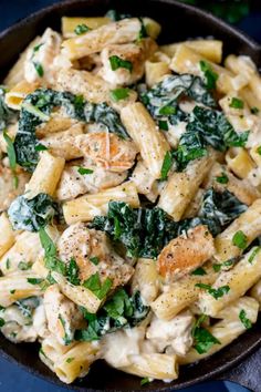 pasta with chicken, spinach and cheese in a skillet on a blue surface