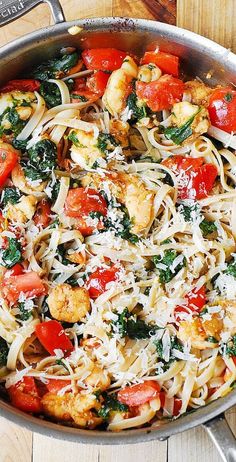 a pan filled with pasta and vegetables on top of a wooden table