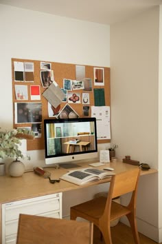 a desktop computer sitting on top of a wooden desk in front of a cork board