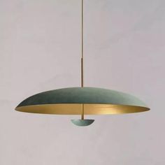 a green and gold pendant light hanging from a ceiling fixture in a white room with grey walls