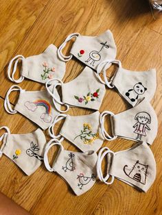 a group of cloth face masks with embroidered designs on them sitting on a wooden floor