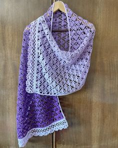 a purple crocheted shawl hanging on a wooden door