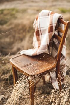 a chair with a blanket on top of it sitting in the middle of a field