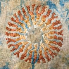 a close up view of an embroidered piece of cloth with orange and blue designs on it