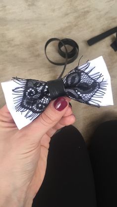 a hand holding a black and white bow tie on top of a piece of paper