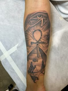 a man's arm with an eye and cross tattoo on the side of his leg