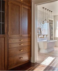 a bathroom with wooden cabinets and white bathtub in the center, along with an open door leading to another room