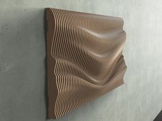 a wall mounted sculpture on the side of a cement wall with wavy lines in it