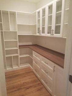 an empty kitchen with white cabinets and wood flooring on the side walk in closet